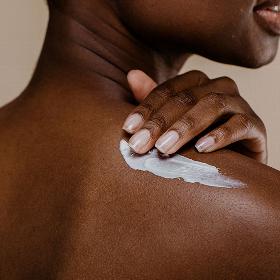 lady rubbing body lotion on her shoulder